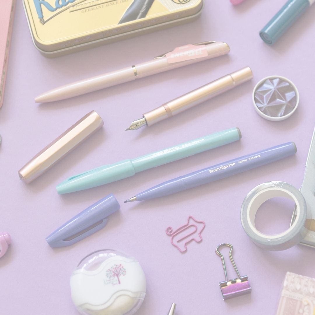 Pastel-colored stationery items including pens and a paper clip on a pink background