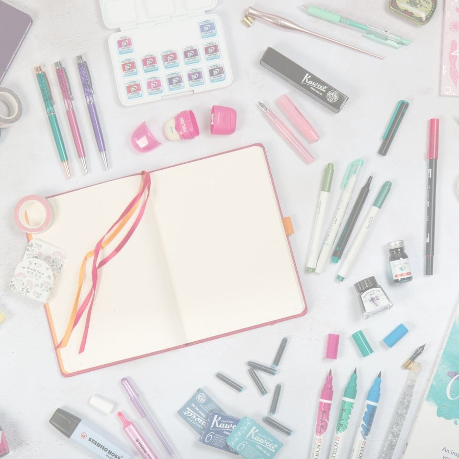 Stationery items including pens, markers, and a notebook on a white surface.