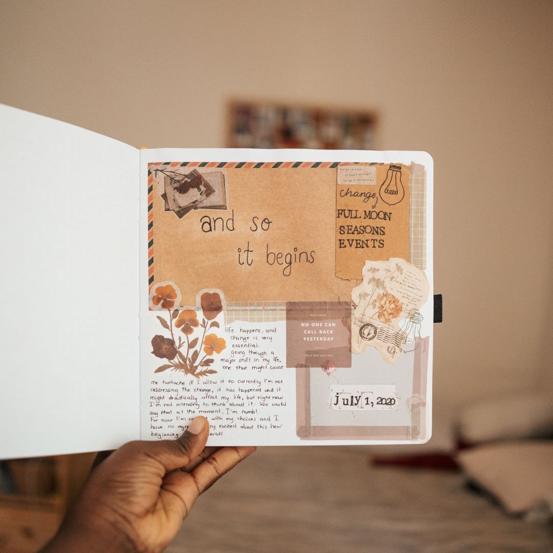 Hand holding a journal with decorative pages and text.
