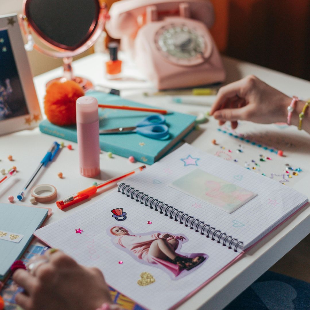 Children's desk with art supplies and a notebook featuring drawings.