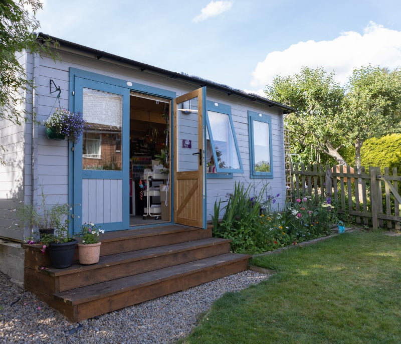 The Rowan Room. Log cabin with door and windows open showing lots of stationery inside.
