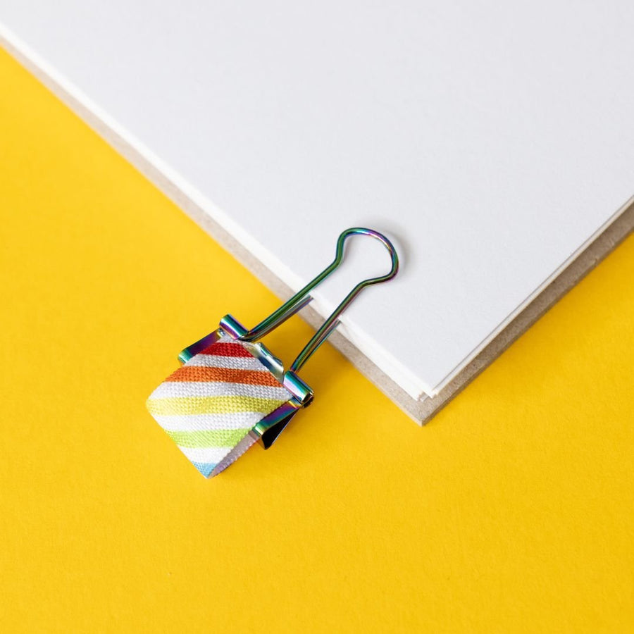 Colourful striped pen clip on a white book with a yellow background